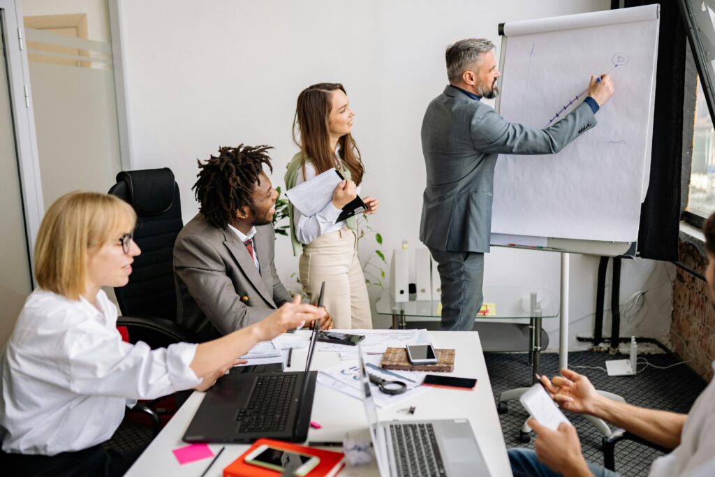 A team leader coaching junior professionals during a strategy discussion in a business office.